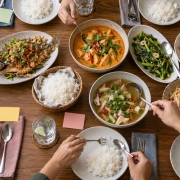 โต๊ะอาหารไทยหลายจานพร้อมช้อนกลางและบัตรสีเปล่าสำหรับวางแผนมื้อกลุ่ม