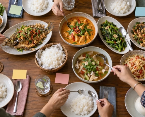โต๊ะอาหารไทยหลายจานพร้อมช้อนกลางและบัตรสีเปล่าสำหรับวางแผนมื้อกลุ่ม