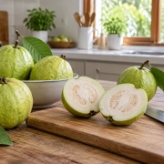 ผลฝรั่งสีเขียวและฝรั่งผ่าครึ่งบนเขียงไม้ในครัว